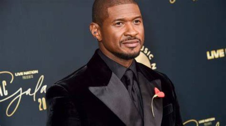 Usher wears black suit, tie, and sunglasses on Met Gala red carpet.